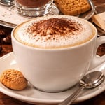 Tasse Cappuccino mit Kakao auf dem Milchschaum, von schräg oben